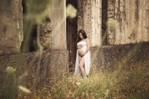 Fotografía de mujer embarazada apoyada en unas ruinas