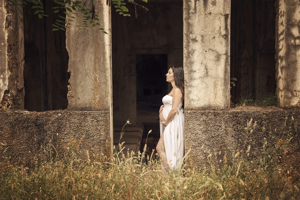 Fotografía de mujer embarazada recostada en unas ruinas