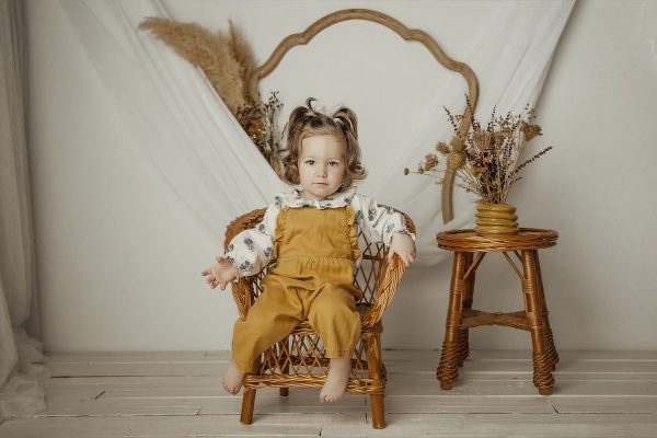 Sin título-7 Fotografía de niña con peto en una silla